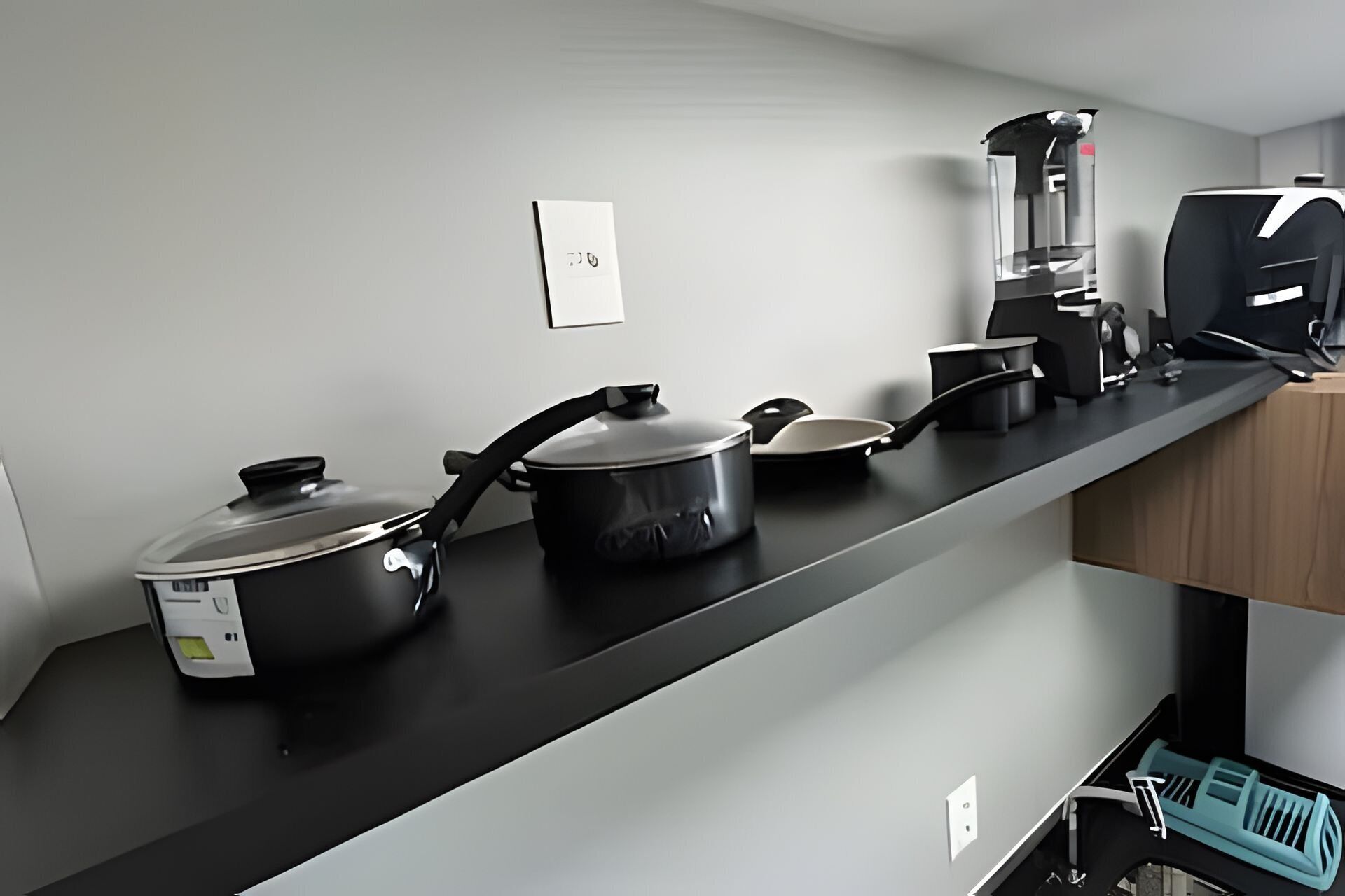 A kitchen with a black countertop, a coffee maker, a kettle, and a pot.