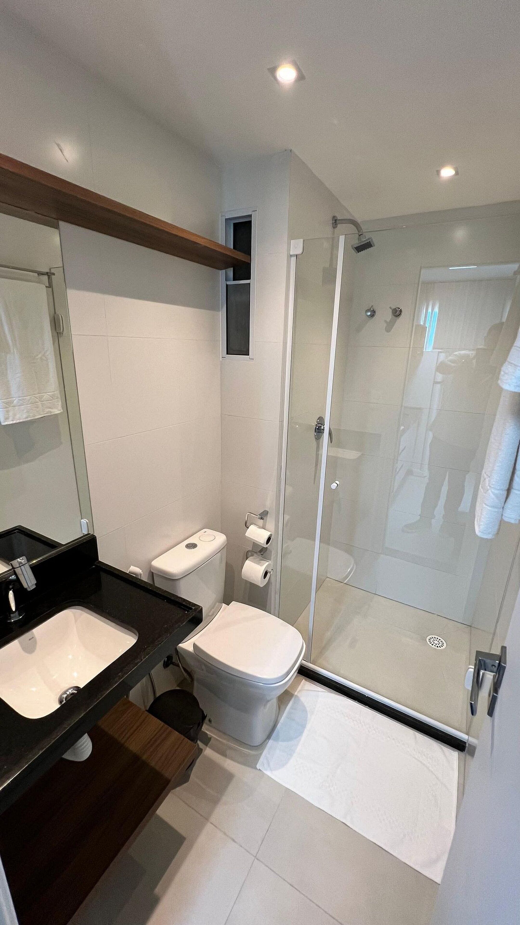 A modern bathroom with a glass-enclosed shower, a dual sink vanity, and a toilet.