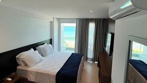 A hotel room with a bed, a TV, and a window with curtains.