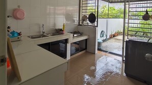 Een keuken met witte tegels, een spoelbak, een fornuis en een raam met uitzicht op een tuin.