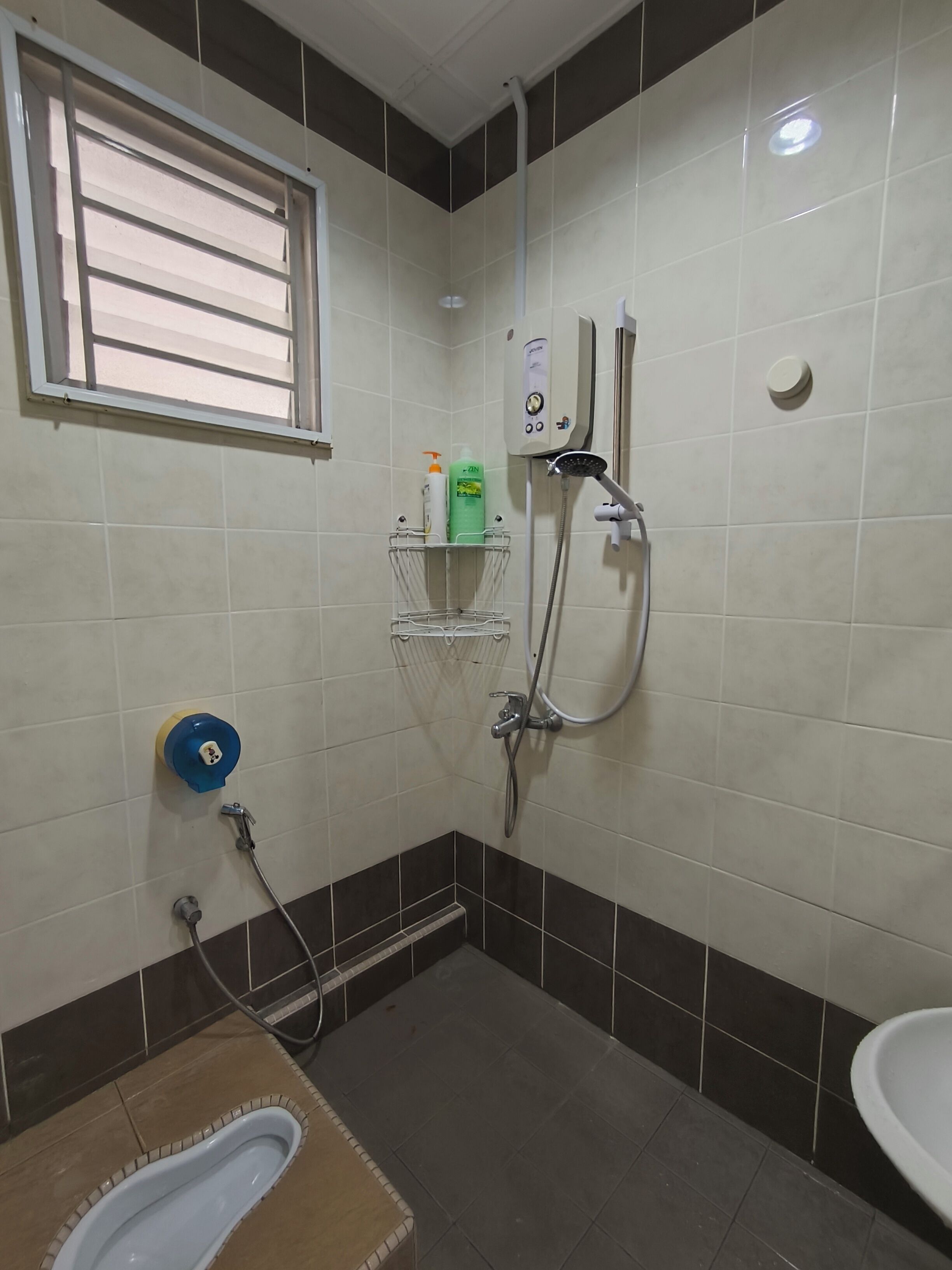 Un baño con ducha, inodoro, lavabo y ventana.