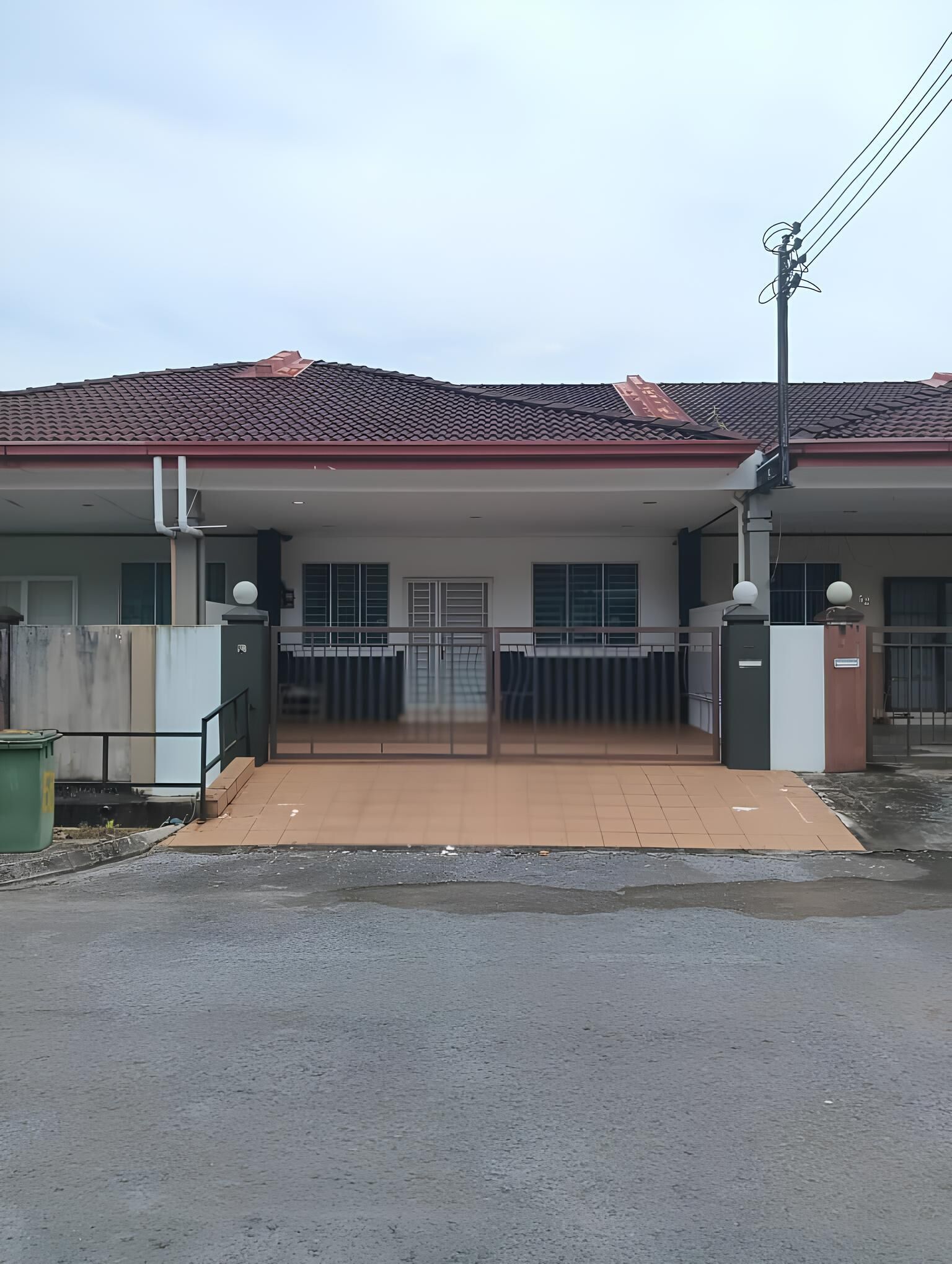 A residential building with a gated entrance, a tiled roof, and a visible utility pole.