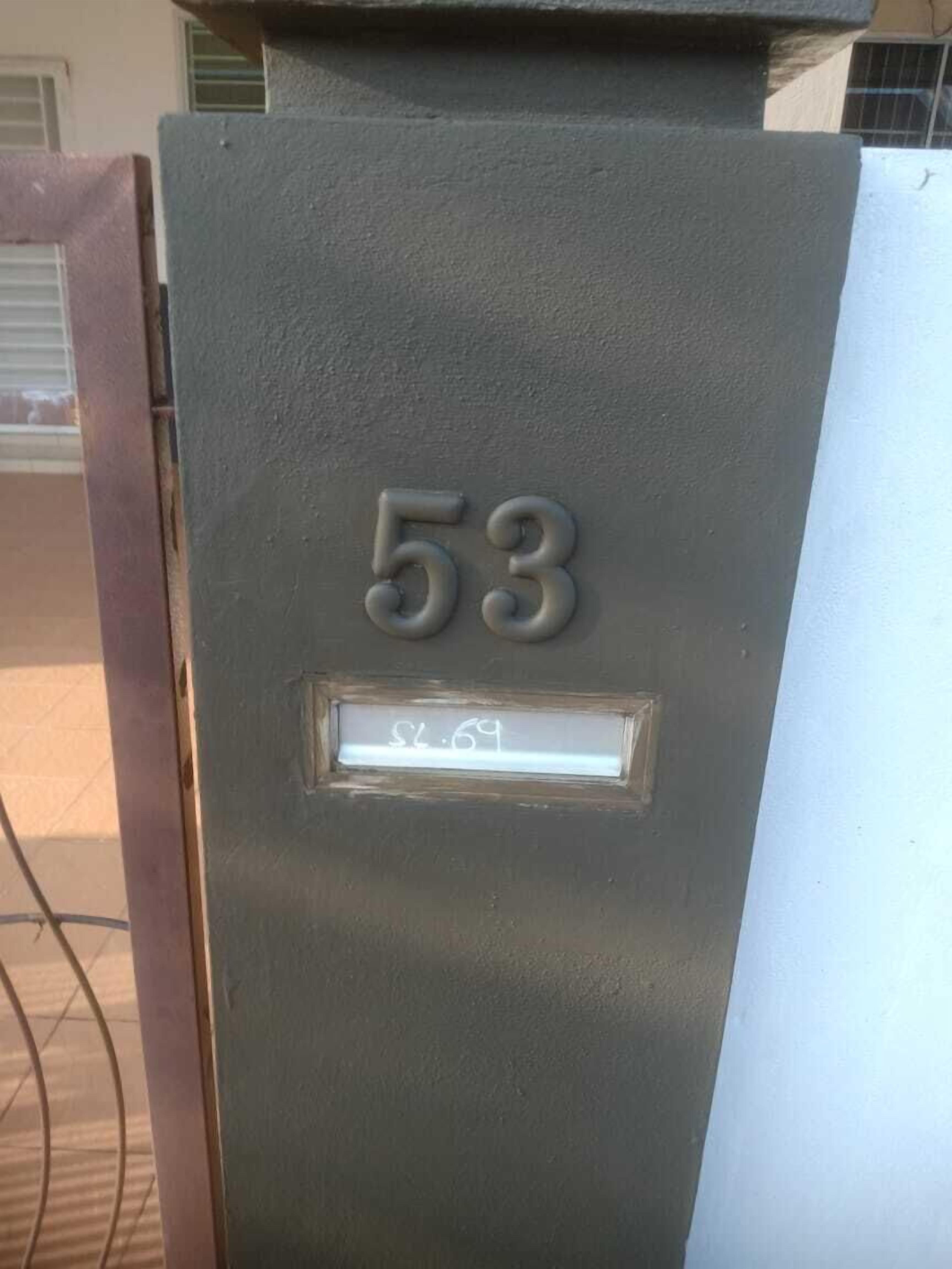 A mailbox with the number 53 and a nameplate with the name 'S. L. 69'.