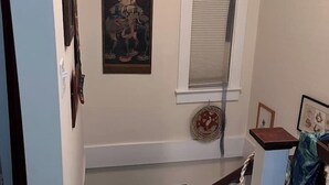 A staircase with a handrail, a wall-mounted picture, and a window with blinds. - Captain's Lookout | Roof Deck & Harbor Views (Gloucester)