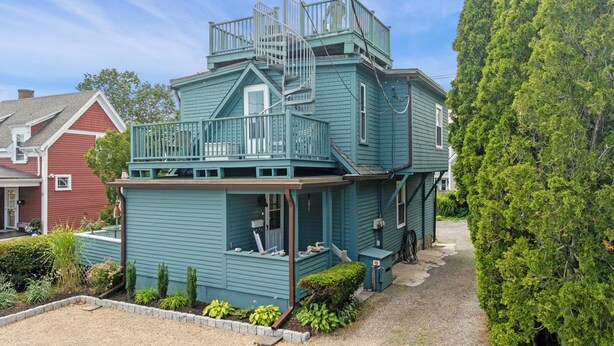 A two-story house with a spiral staircase, a porch, and a small garden area. - Captain's Lookout | Roof Deck & Harbor Views (Gloucester)