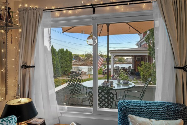 A room with a large window, a table with chairs, and a lamp.