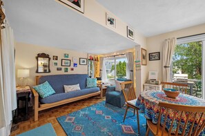 Een gezellige woonkamer met een bank, stoelen, een eettafel en uitzicht op de omgeving.