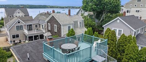 A residential property with a balcony, a view of the water, and a large tree.