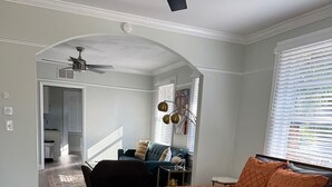Un dormitorio con una cama grande, un escritorio y una silla. Cuenta con una ventana con persianas y un ventilador de techo.