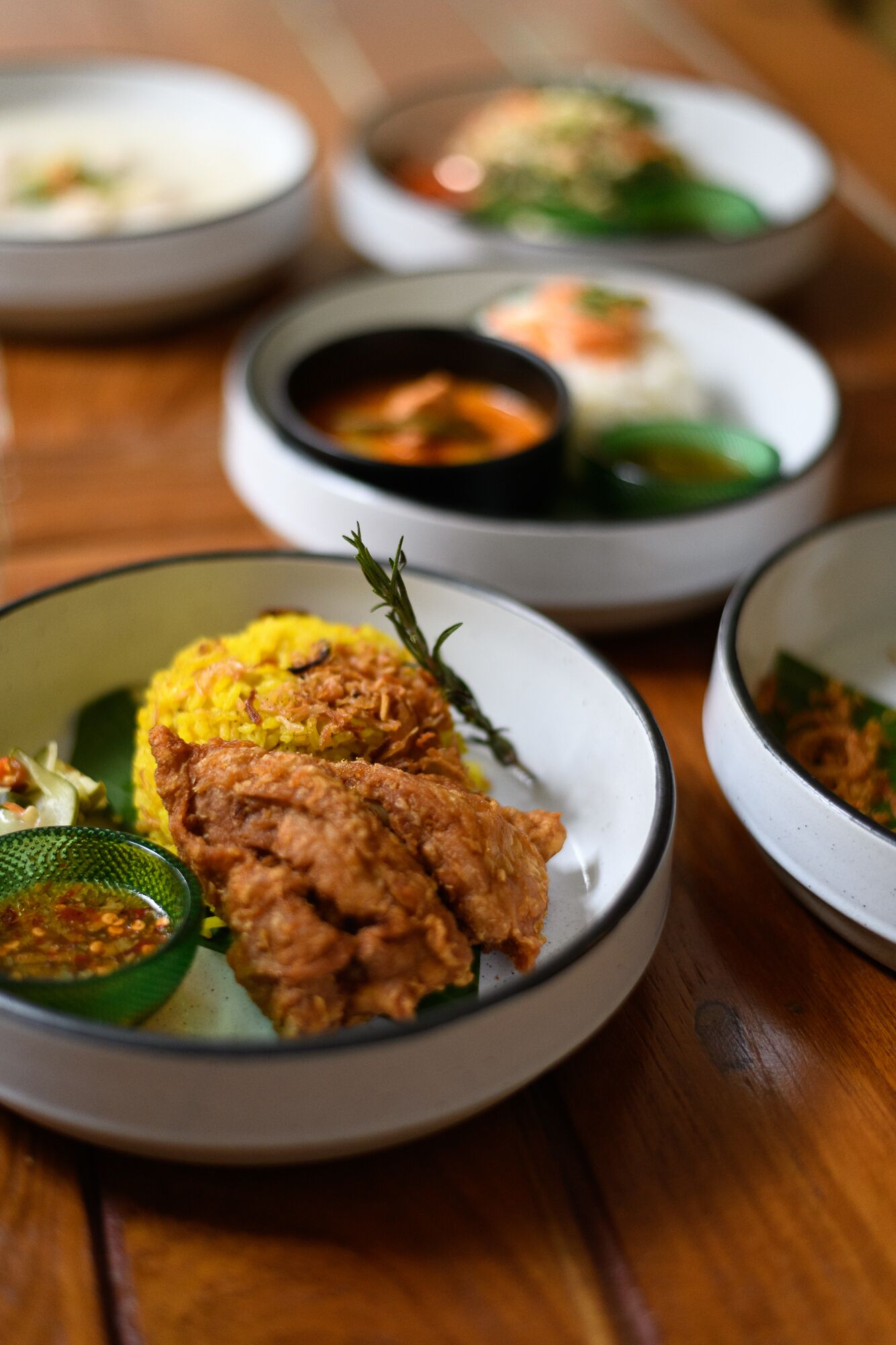 Una mesa con varios platos, incluyendo arroz amarillo, pollo frito y diferentes acompañamientos.