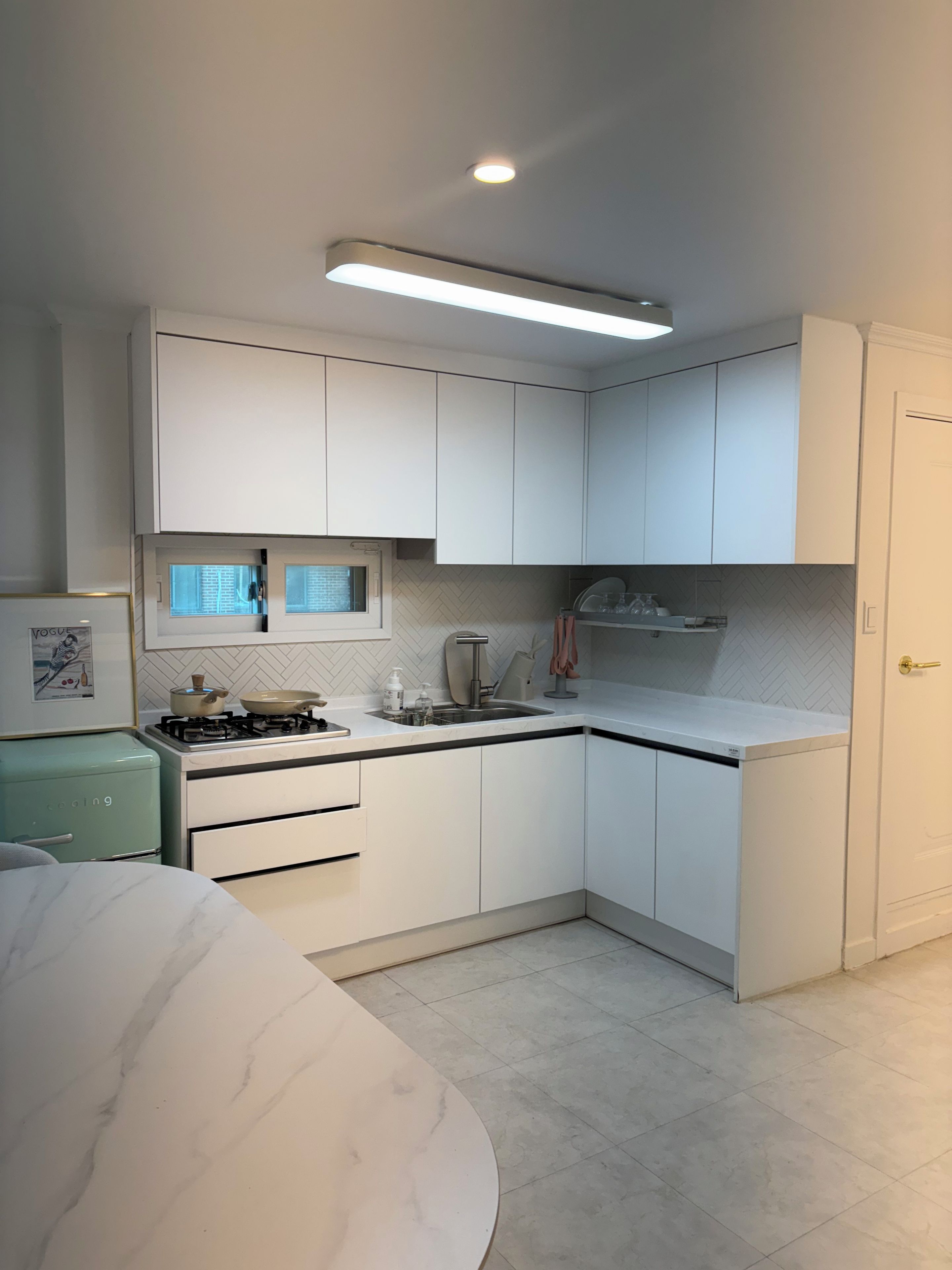 A modern kitchen with white cabinets, a gas stove, and a herringbone-patterned backsplash.