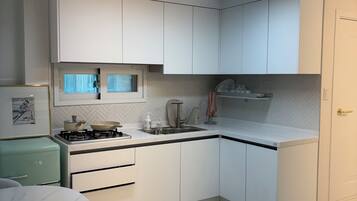 A modern kitchen with white cabinets, a gas stove, and a herringbone-patterned backsplash.