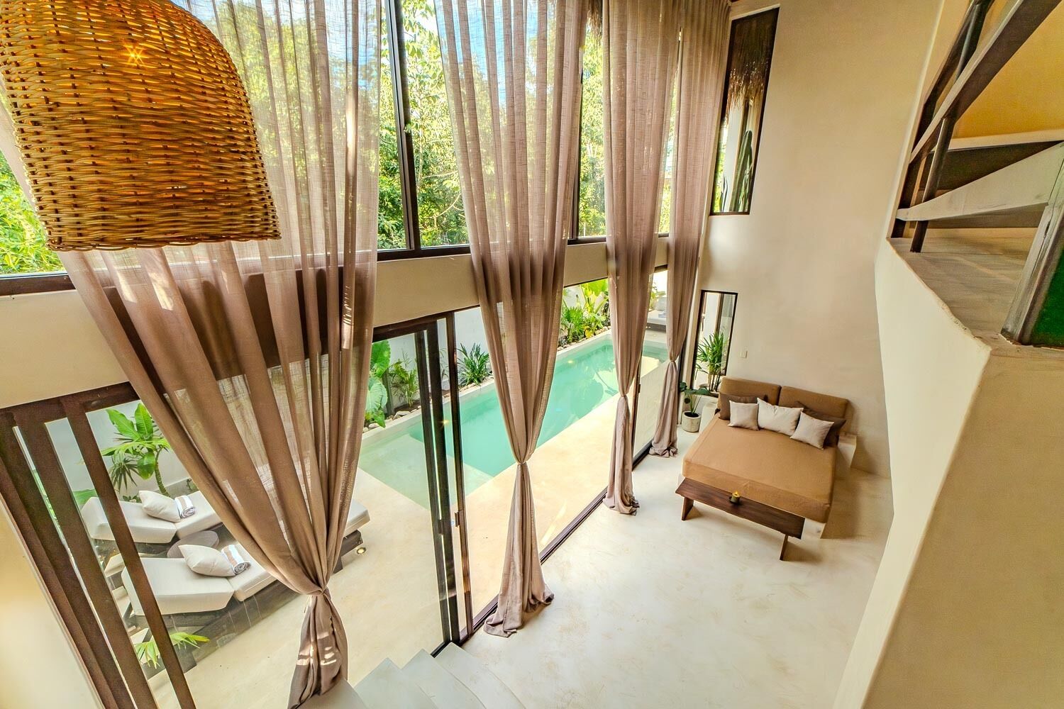 A bedroom with a view of a swimming pool, large windows, and a staircase leading to an outdoor area.