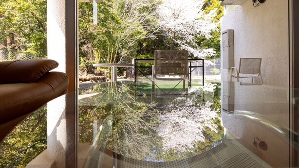 A glass-enclosed infinity pool with a view of a garden and trees. - Higashi Kumamoto Business Center (Ozu)