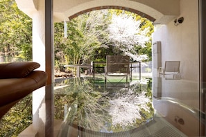 A glass-enclosed infinity pool with a view of a garden and trees. - Higashi Kumamoto Business Center (Ozu)