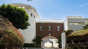 A building with a curved facade and a brick entrance. - Higashi Kumamoto Business Center (Ozu)