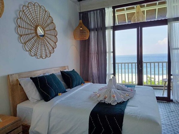 A hotel room with a large bed, a decorative wall piece, and a view of the ocean through a sliding door. - The sagara villa (Penida Island)
