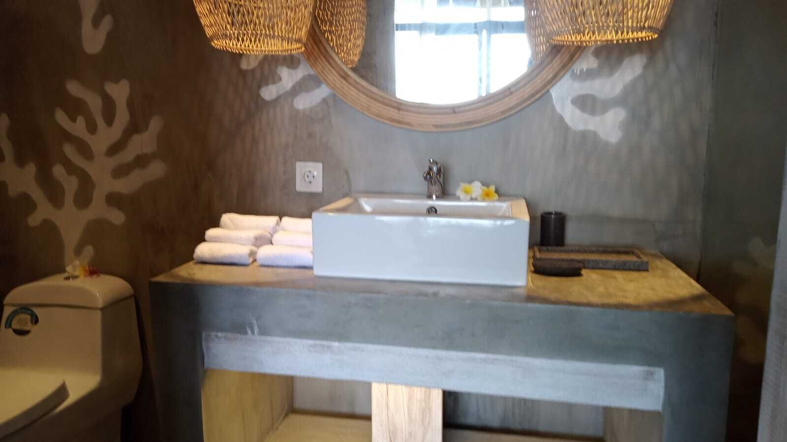 A bathroom with a rectangular sink, white towels, a toilet, and a window with a wooden frame.