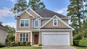 A two-story house with a garage, a stone foundation, and a well-maintained lawn. - Wonderful 4B2.5B for Augusta Master Holiday (Evans)
