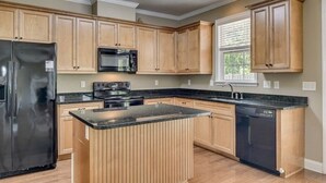 A kitchen with wooden cabinets, a black refrigerator, a microwave, a stove, and a dishwasher. - Wonderful 4B2.5B for Augusta Master Holiday (Evans)