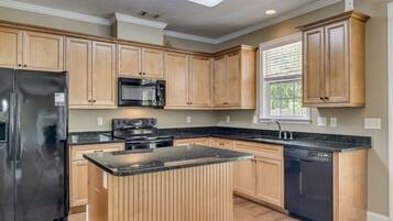 A kitchen with wooden cabinets, a black refrigerator, a microwave, a stove, and a dishwasher.