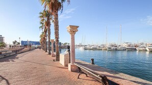 A marina with boats docked, a brick walkway, palm trees, and a casino building in the background.