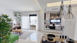A modern apartment with a dining area, kitchen, and living space.
