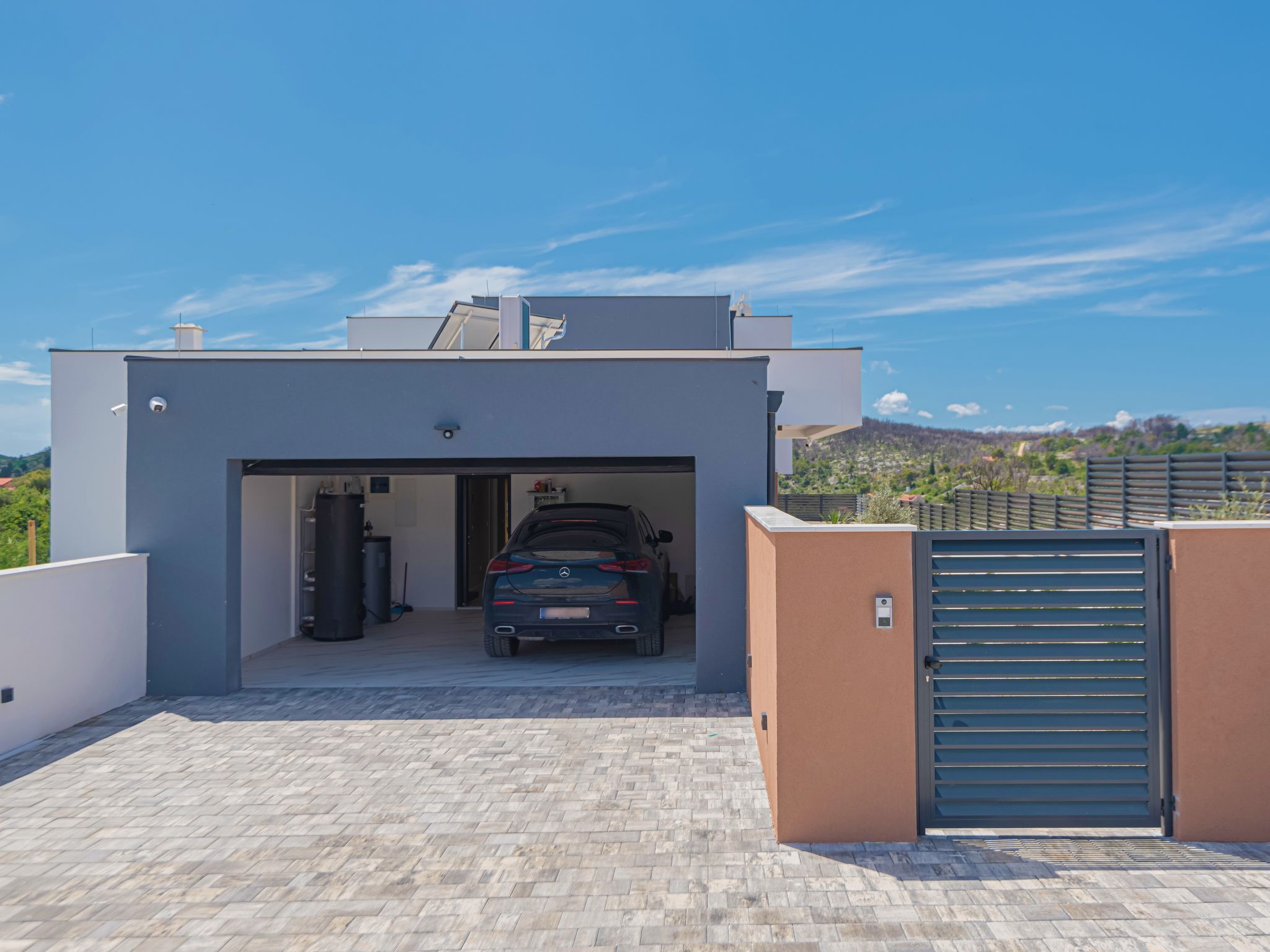 A modern garage with a car parked inside, a security camera, and a gated entrance.