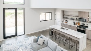 Una cocina moderna con una isla central, taburetes de bar y un área de comedor con sofá.