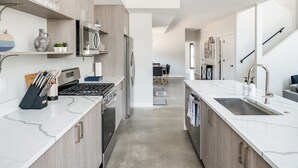 Una cocina moderna con encimeras de mármol blanco, electrodomésticos de acero inoxidable y armarios de madera.