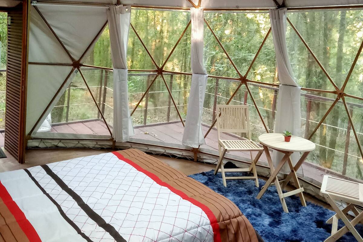 A tent with a bed, a small table, and a chair.