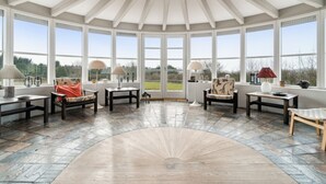 A conservatory with a high ceiling, large windows, and a stone floor. - "Herlek" - 450m from the sea by Interhome (Aakirkeby)