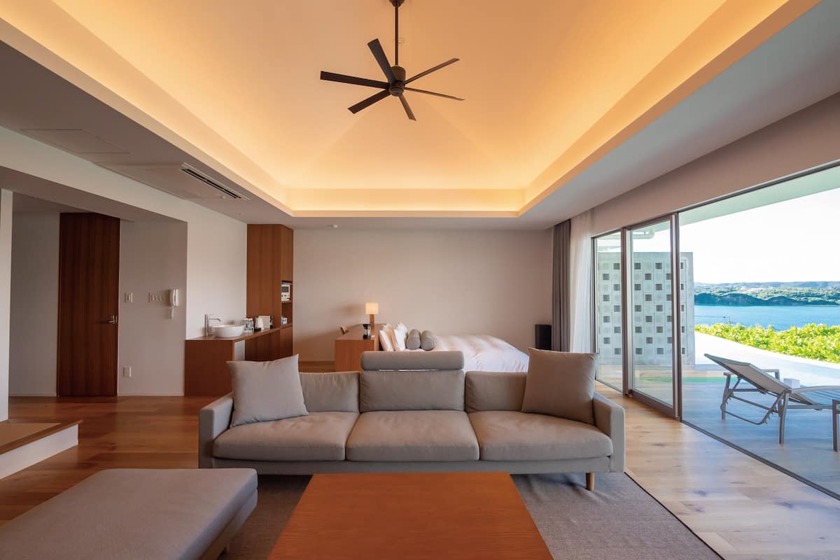 Een moderne hotelkamer met een groot bed, een bank, een bijzettafeltje en uitzicht op zee.
