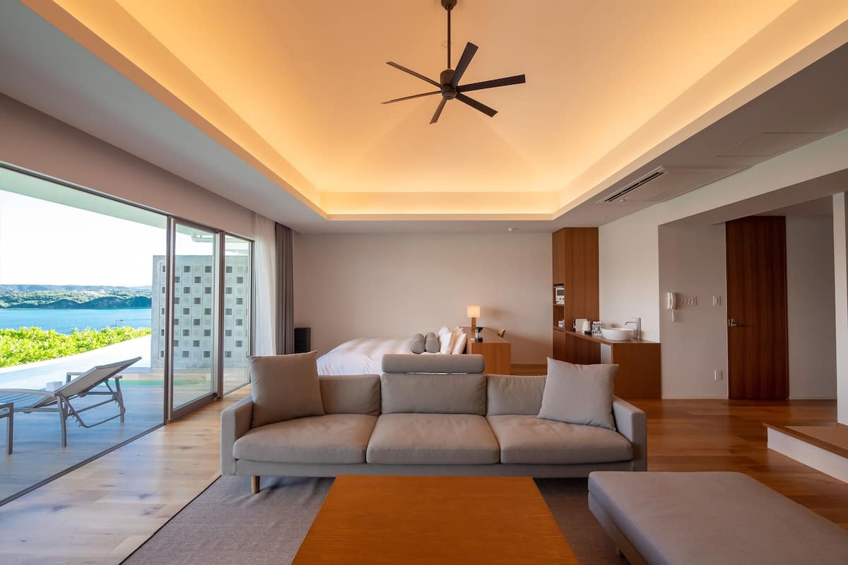 Een moderne hotelkamer met een groot bed, een slaapbank, een eethoek en uitzicht op zee.