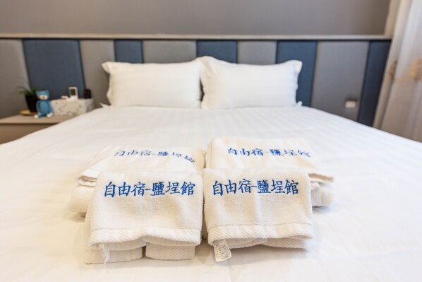 Cama bem arrumada com duas toalhas dobradas ao pé, cada uma com texto em japonês.