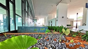 Un ambiente interno moderno con zona salotto, elemento d'acqua e diverse piante.