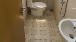 A small bathroom with a toilet, a shower, and a sink.