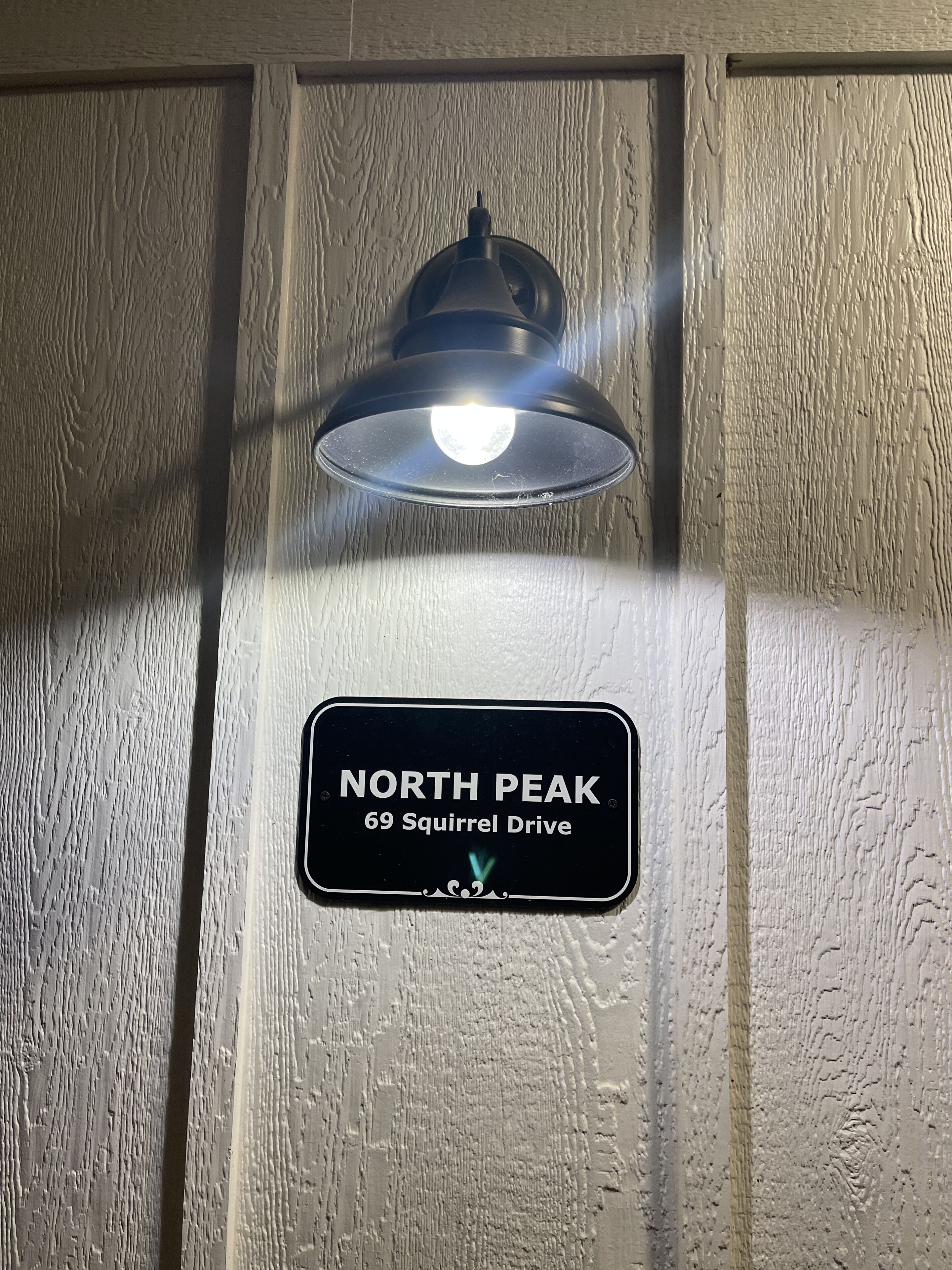 Una lámpara fijada a la pared y un cartel que dice "NORTH PEAK 69 Squirrel Drive".