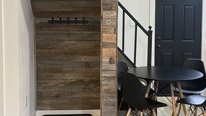 Un comedor con una mesa y sillas negras, una pared de madera y una puerta negra.