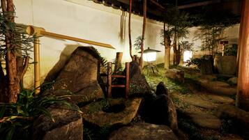 A traditional Japanese garden with rock formations, bamboo, and a wooden bridge.