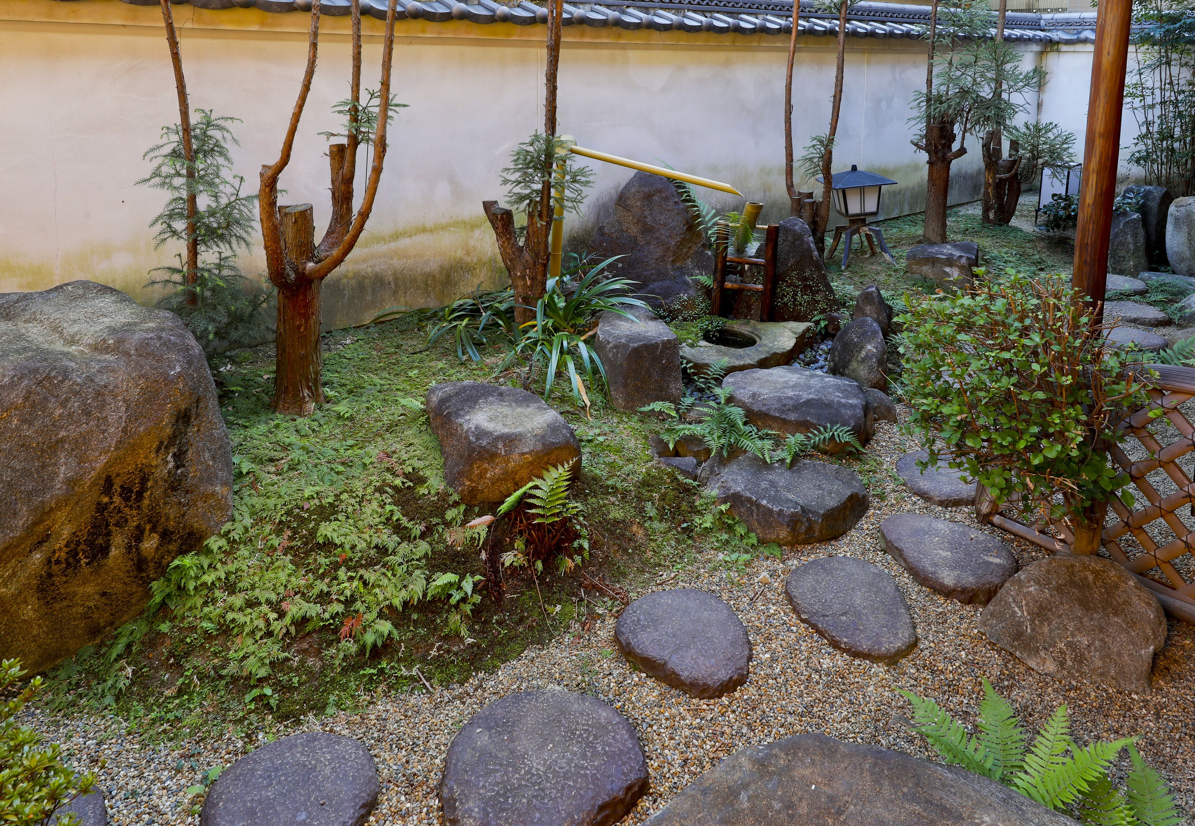 En traditionell japansk trädgård med stenformationer, bambu och en lykta.