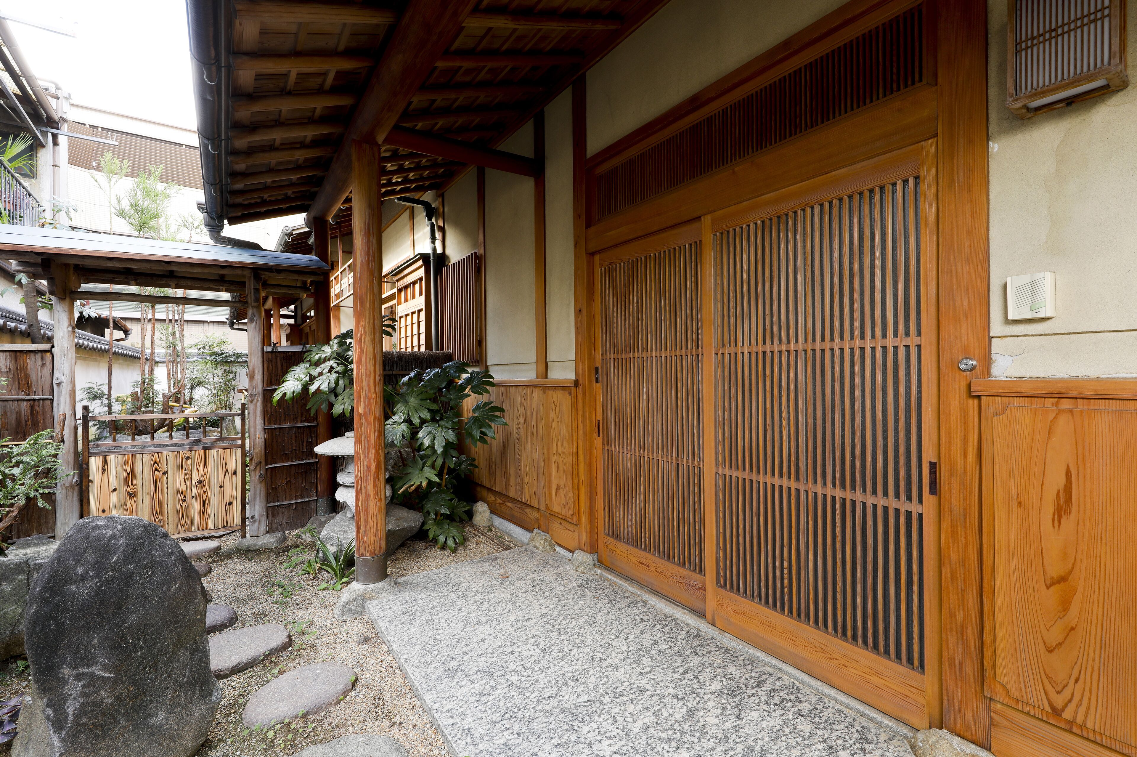 A traditional Japanese building with a wooden gate, stone steps, and a tiled walkway.