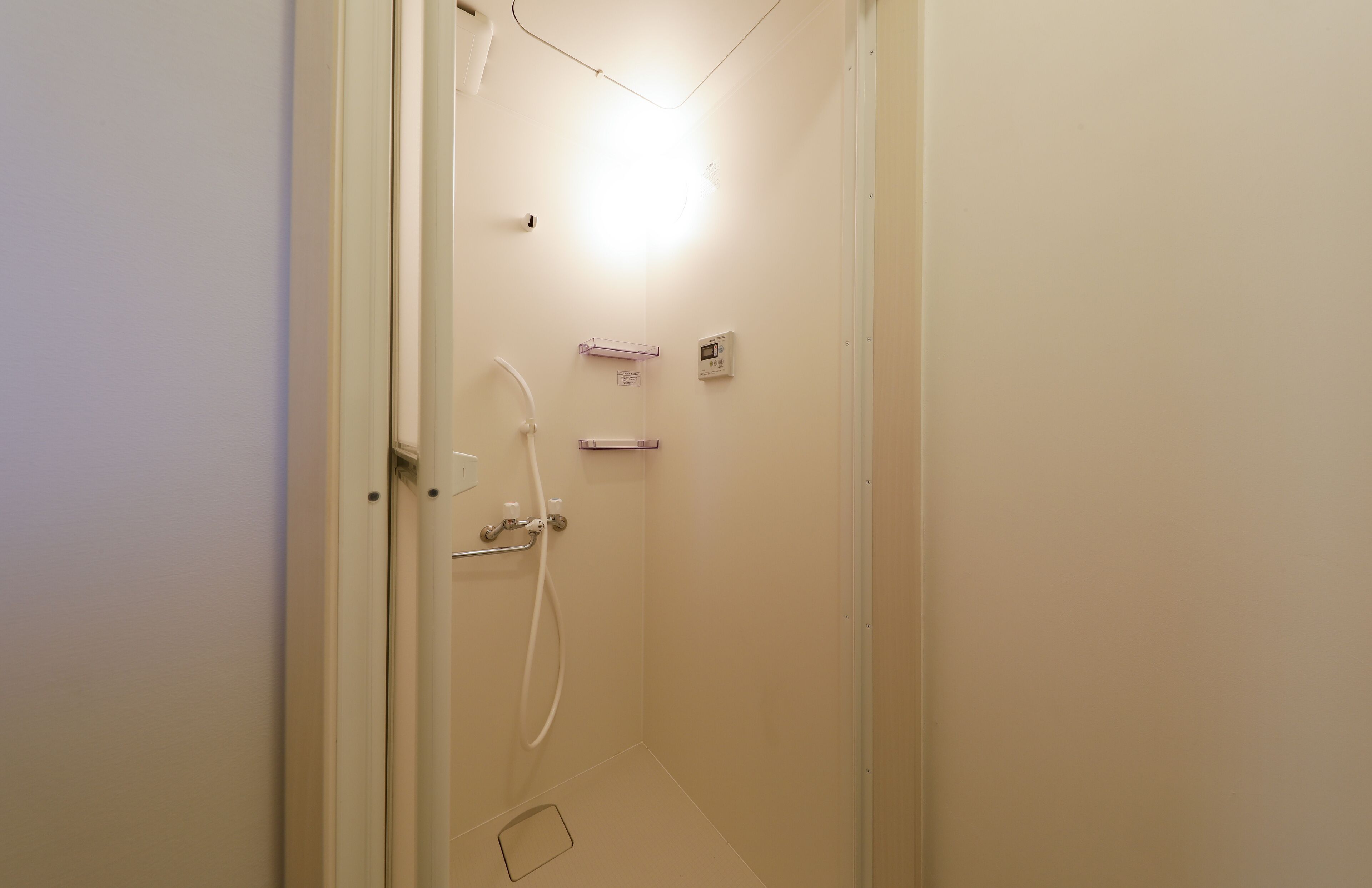 A small, well-lit bathroom with a shower, a toilet, and a sink.