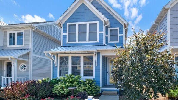 A two-story house with a blue exterior, white trim, and a front porch with a bird bath. - Zuzu's Petals 3 bed 4 bath (Ottawa)