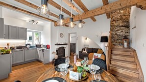 A spacious living area with a wooden staircase, a dining table set for six, and a kitchen in the background. - Casa Oliva - Boutique Townhouse in Ascona (Ascona)