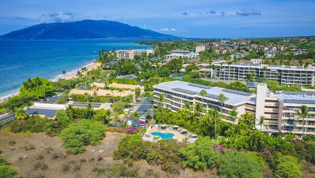 Un resort con piscina, spiaggia privata e una montagna sullo sfondo.