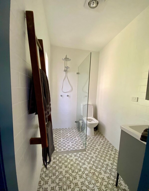 Une salle de bain avec douche, toilettes et une paroi en verre.