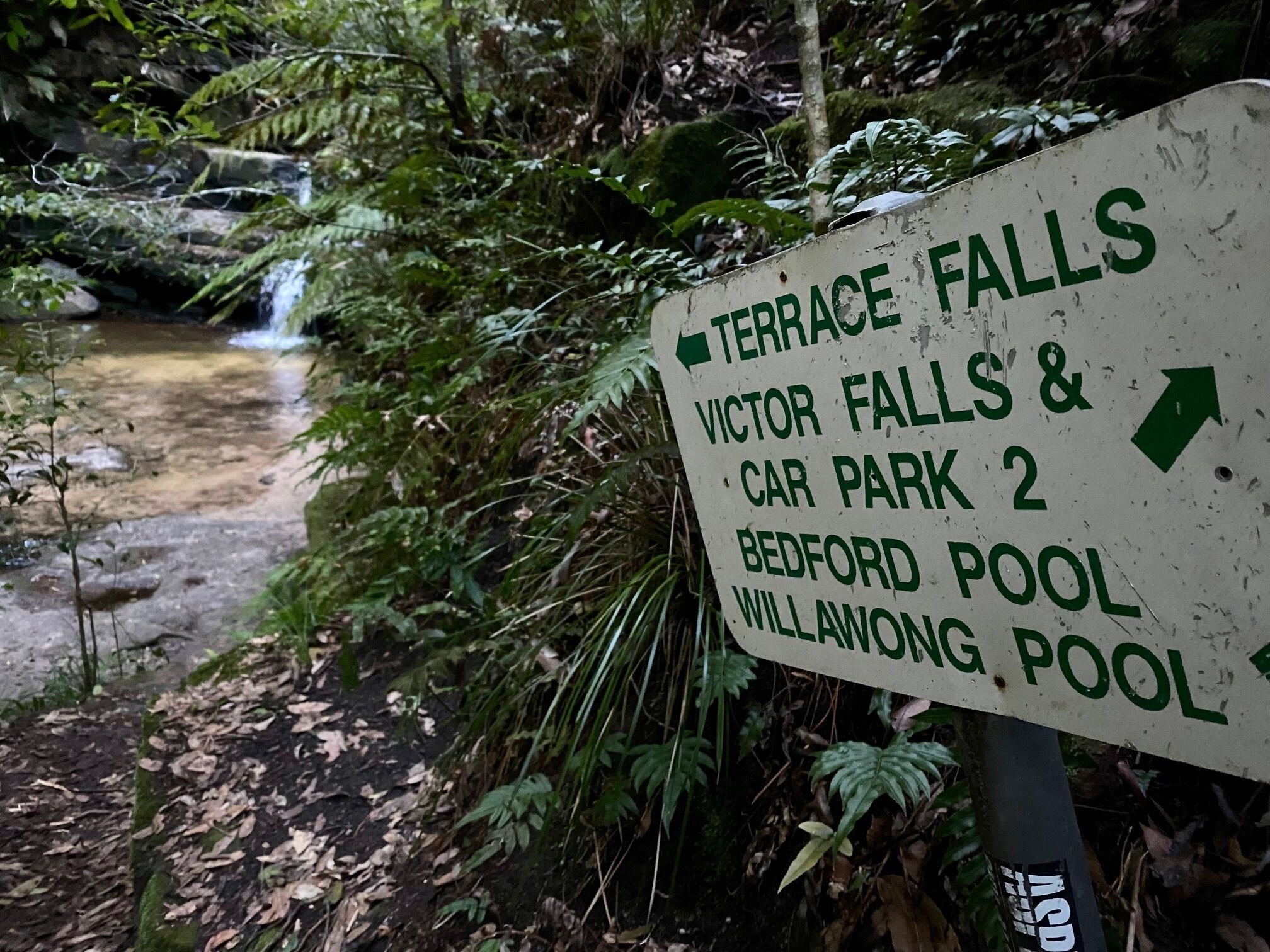 A sign with directions to Terrace Falls, Victor Falls & Car Park 2, Bedford Pool, and Willawong Pool.