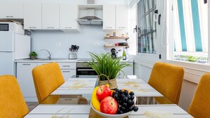 Una cocina moderna con armarios blancos, una campana de acero inoxidable y un ventanal con cortinas a rayas.