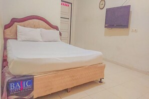 A bed with a wooden frame and white bedding, a clock on the wall, and a television mounted above it. - OYO Life 93590 Penginapan Palapa 10 Syariah (Bandar Lampung)